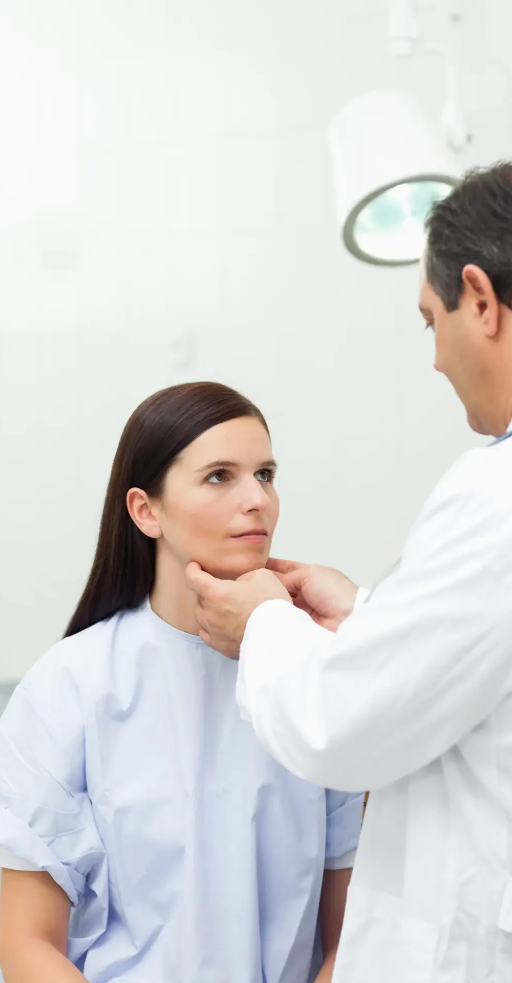 Doctor touching the neck of a patient in an examination room